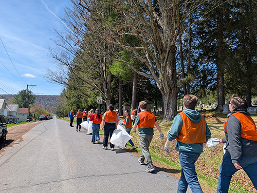 Students cleaning neighborhood streets wearing safety vests