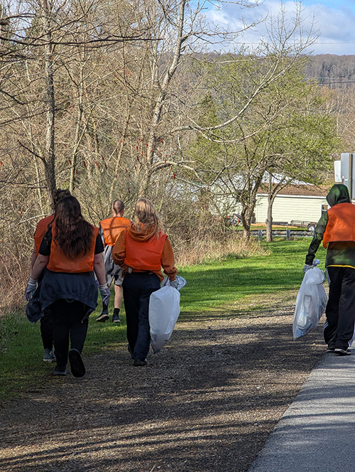 Group of happy students walking and looking for trash to remove