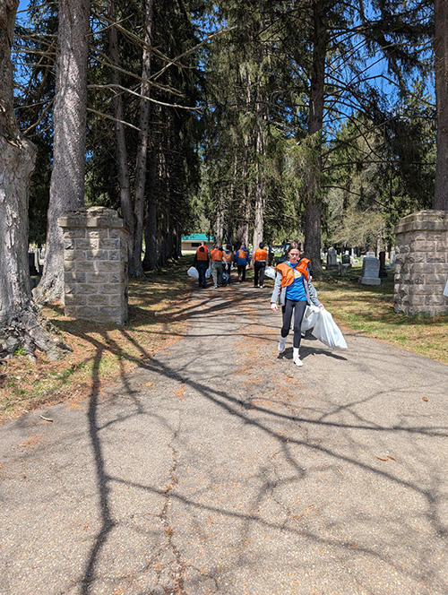 Student outside holding a trash bag