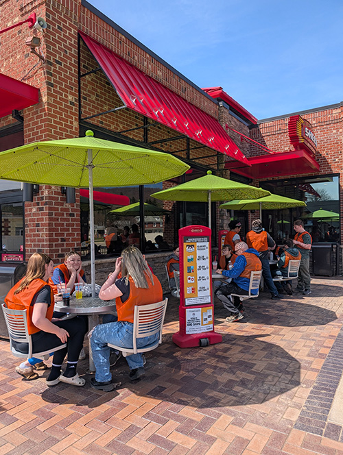 Students sitting at round tables outside a restaurant