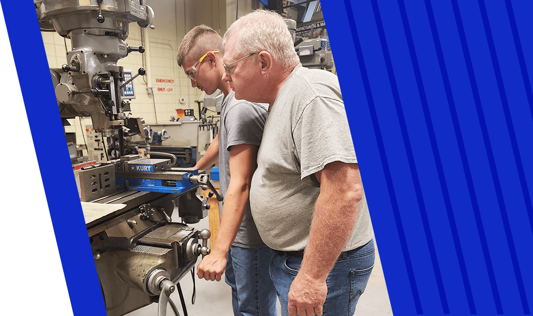 Instructor watching over student using machinery in garage classroom