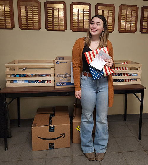 Female student holding American flag next to donations