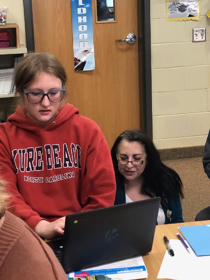 Student using laptop next to guest speaker