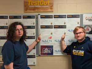 James and Zachery pointing at their certificates on the wall