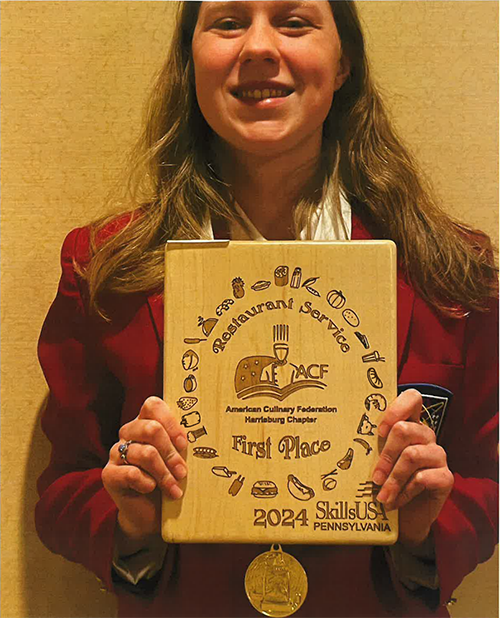 Anastasia wearing a medal and holding up a certificate