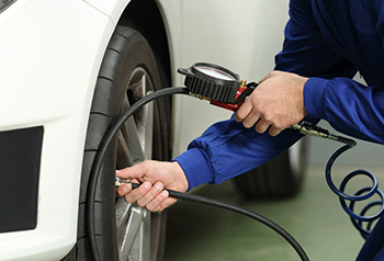 Close up of technician measuring tire pressure